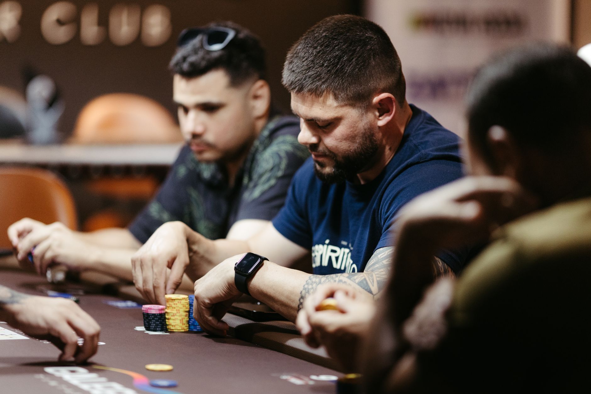 Joueurs concentrés sur une partie de poker à une table de casino, montrant des stratégies intenses et de la concentration.