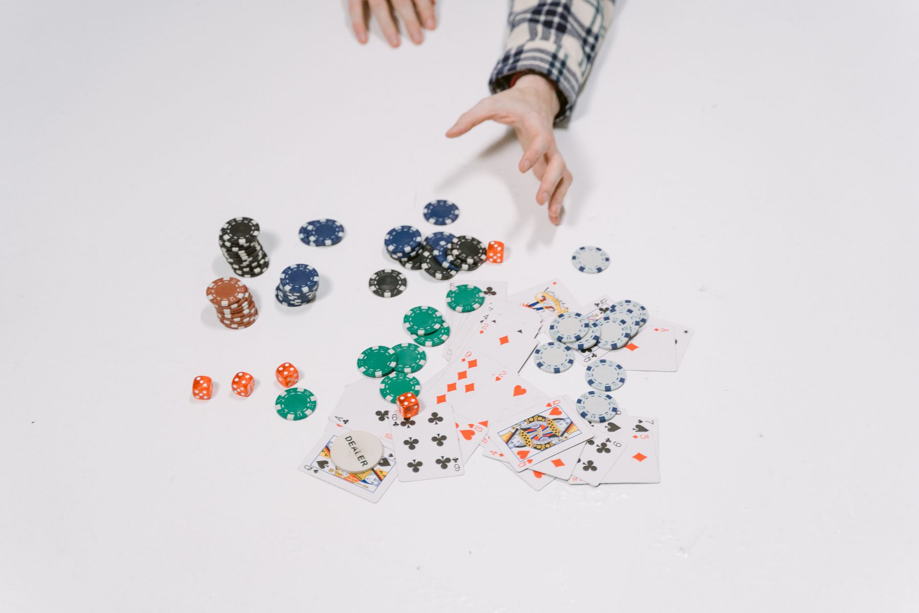 Gros plan sur des jetons de poker et des cartes sur une surface blanche, capturant un moment d'une partie de cartes.
